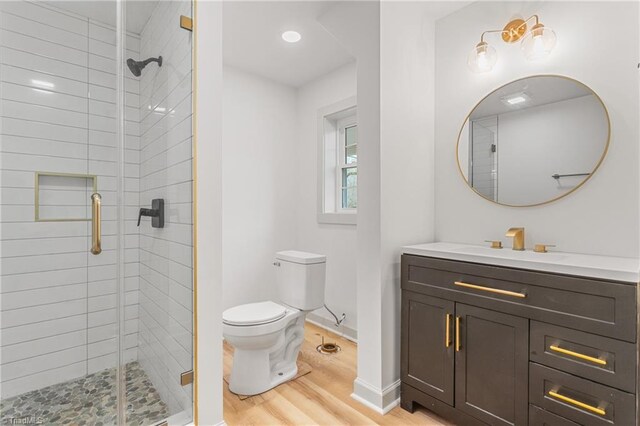 bathroom with an enclosed shower, hardwood / wood-style floors, vanity, and toilet