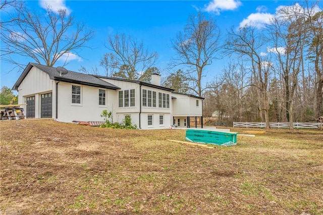 rear view of house with a garage and a yard