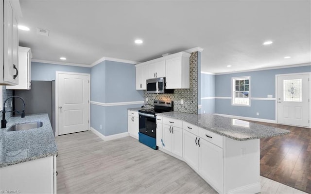 kitchen with white cabinets, sink, stainless steel appliances, and kitchen peninsula