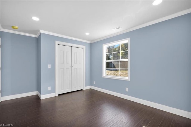 unfurnished bedroom with ornamental molding, a closet, and dark hardwood / wood-style flooring