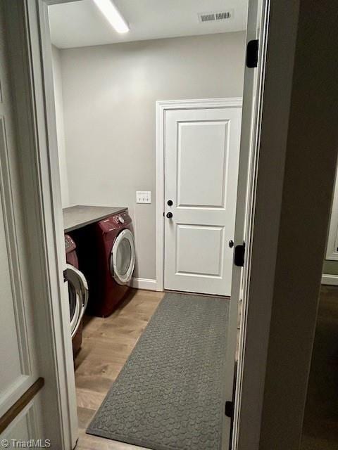 laundry room featuring washer and clothes dryer and light hardwood / wood-style floors