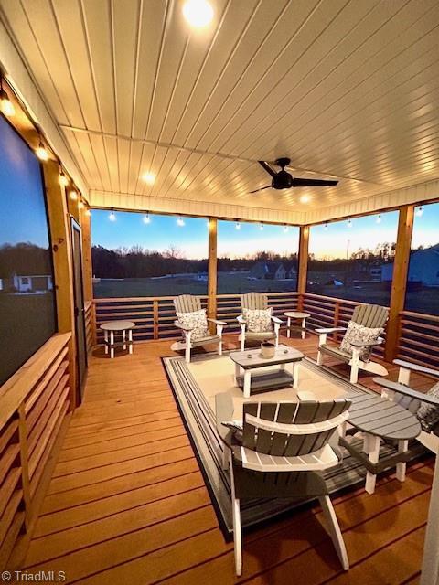 deck at dusk featuring ceiling fan