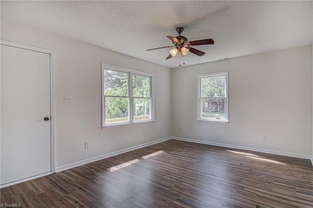 empty room with a textured ceiling, dark wood-type flooring, and ceiling fan