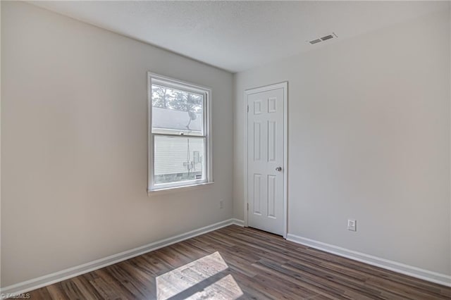 spare room featuring dark wood-type flooring and a textured ceiling