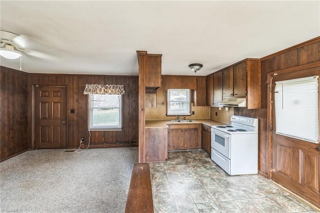 kitchen with white electric range oven, sink, light carpet, and wood walls