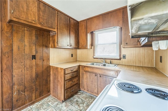 kitchen featuring light tile patterned floors, wood walls, sink, and white range