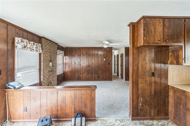 interior space featuring ceiling fan, wooden walls, and light colored carpet