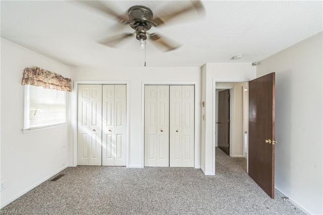 unfurnished bedroom with multiple closets, carpet, and ceiling fan