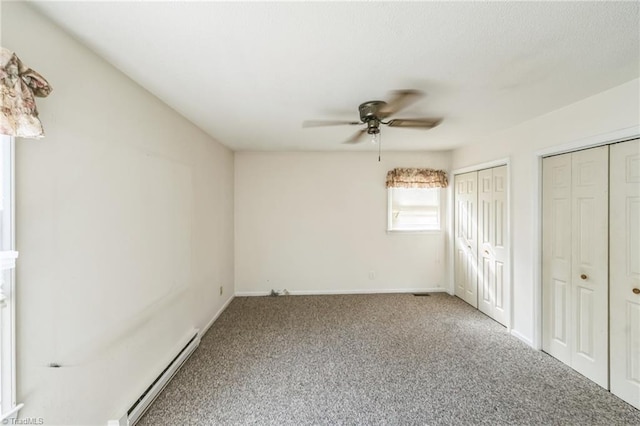 unfurnished bedroom with a baseboard radiator, carpet, multiple closets, and ceiling fan