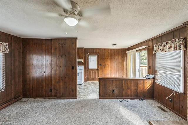 empty room featuring a textured ceiling, ceiling fan, light colored carpet, and wooden walls