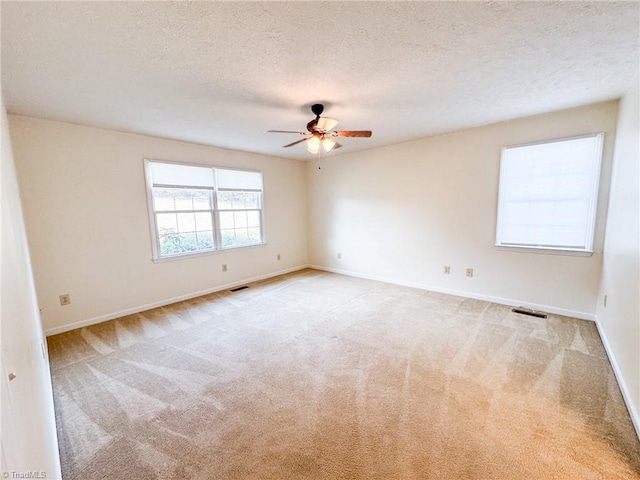 spare room with ceiling fan, light colored carpet, and a textured ceiling