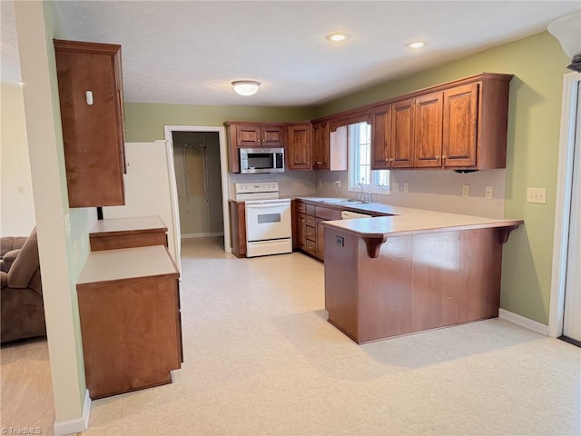 kitchen featuring sink, a breakfast bar, kitchen peninsula, and white range with electric cooktop