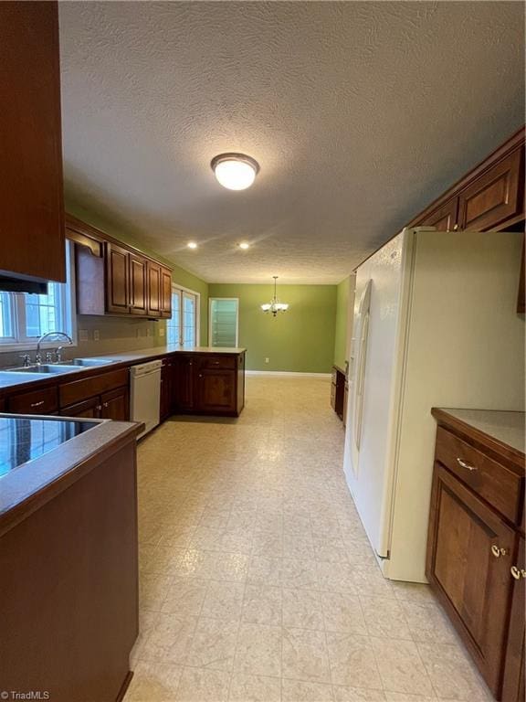 kitchen with sink, decorative light fixtures, a chandelier, a wealth of natural light, and white appliances