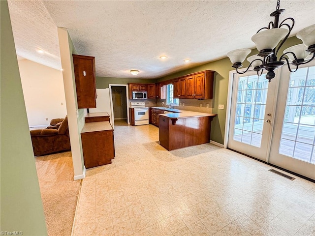 kitchen featuring white electric range, a breakfast bar area, an inviting chandelier, fridge, and kitchen peninsula