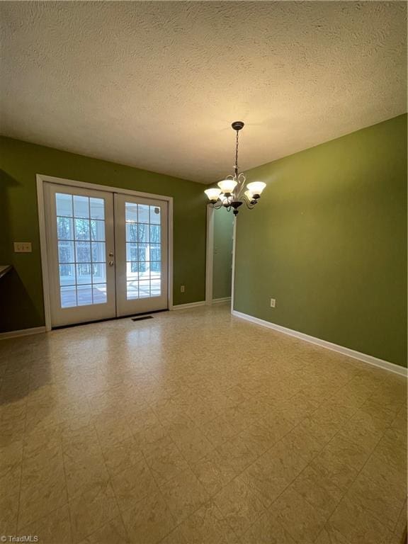 unfurnished room with french doors, a chandelier, and a textured ceiling