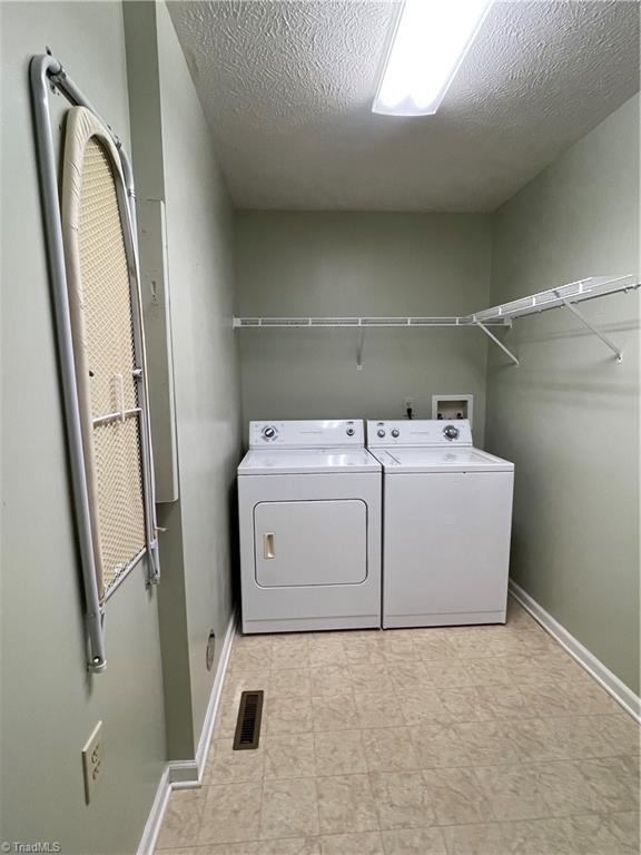 laundry area with separate washer and dryer and a textured ceiling