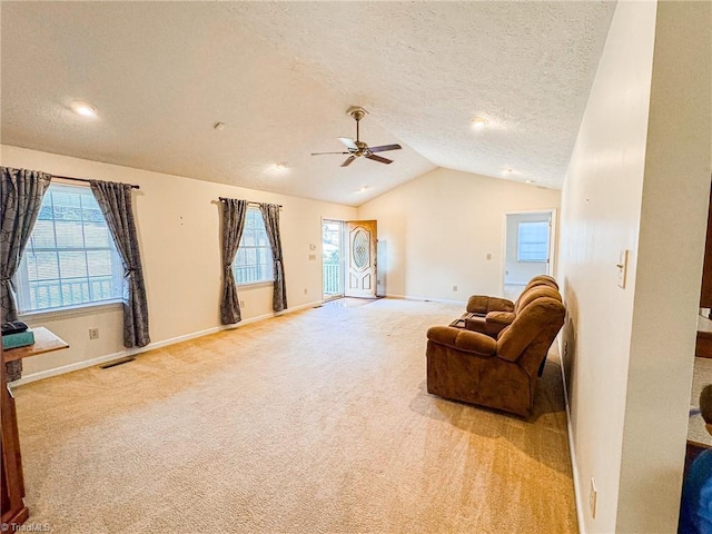 sitting room with ceiling fan, light colored carpet, lofted ceiling, and a textured ceiling