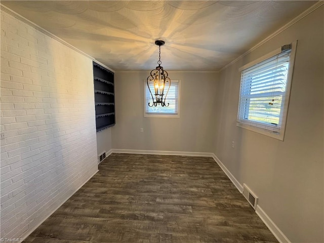 unfurnished dining area with ornamental molding, dark hardwood / wood-style flooring, brick wall, and a notable chandelier