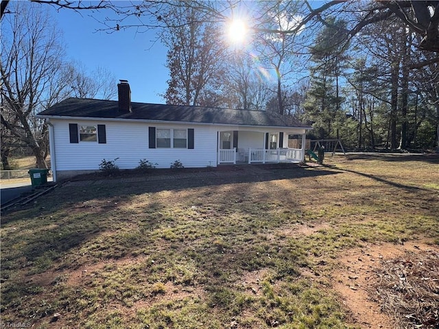 back of property with covered porch and a yard