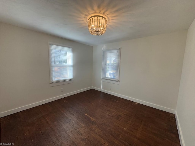 unfurnished room featuring dark wood-type flooring and a chandelier