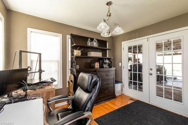 office area featuring light wood-style floors, a wealth of natural light, french doors, and a chandelier