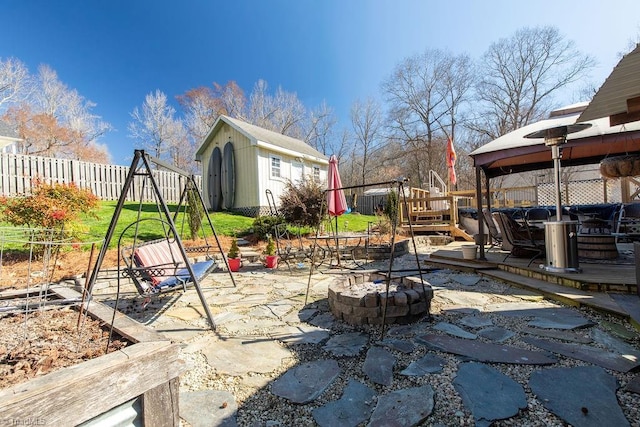 view of patio / terrace featuring an outbuilding, a storage shed, an outdoor fire pit, and fence