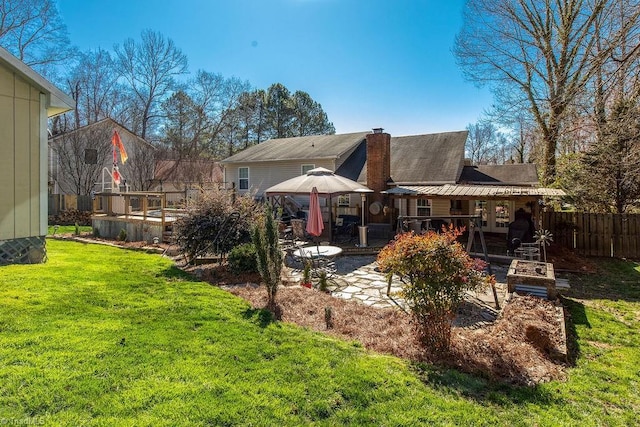 rear view of house featuring a chimney, fence, a lawn, and a patio