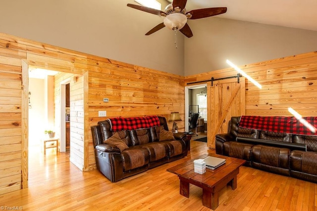 living area featuring a barn door, wooden walls, and wood finished floors