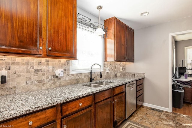 kitchen featuring tasteful backsplash, baseboards, dishwasher, light stone countertops, and a sink