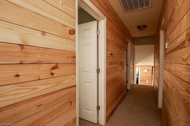 hall featuring carpet, visible vents, and wooden walls