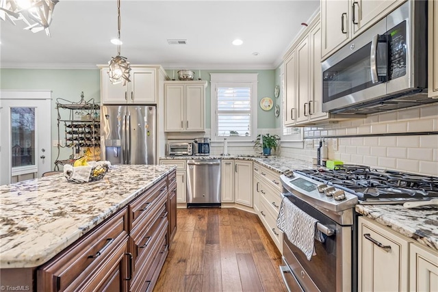 kitchen featuring pendant lighting, ornamental molding, dark hardwood / wood-style floors, and appliances with stainless steel finishes