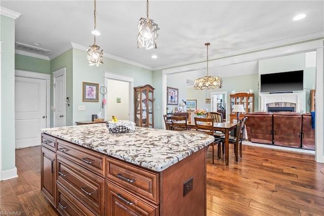 kitchen featuring hanging light fixtures, crown molding, dark wood-type flooring, and a center island