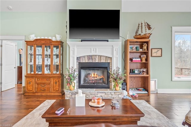 living room with a stone fireplace and dark hardwood / wood-style floors