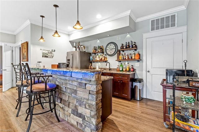 bar featuring sink, ornamental molding, light stone counters, stainless steel fridge with ice dispenser, and light hardwood / wood-style flooring