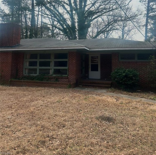 ranch-style house with brick siding, a porch, and a chimney