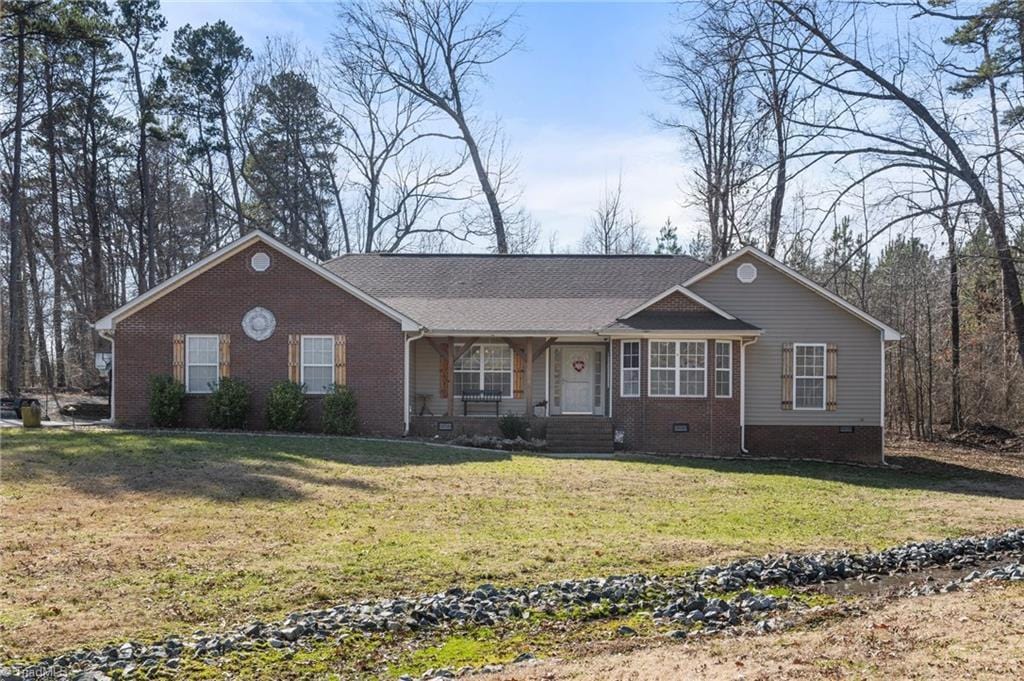 ranch-style home featuring covered porch and a front yard