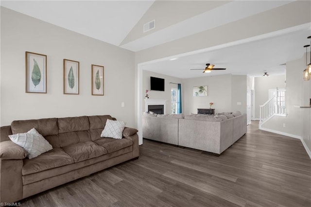 living room featuring visible vents, dark wood finished floors, a fireplace, and stairs