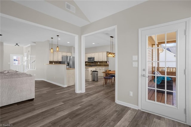 unfurnished living room with vaulted ceiling, baseboards, visible vents, and dark wood-style flooring
