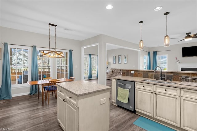 kitchen featuring light stone countertops, dark wood-style flooring, a sink, stainless steel dishwasher, and open floor plan