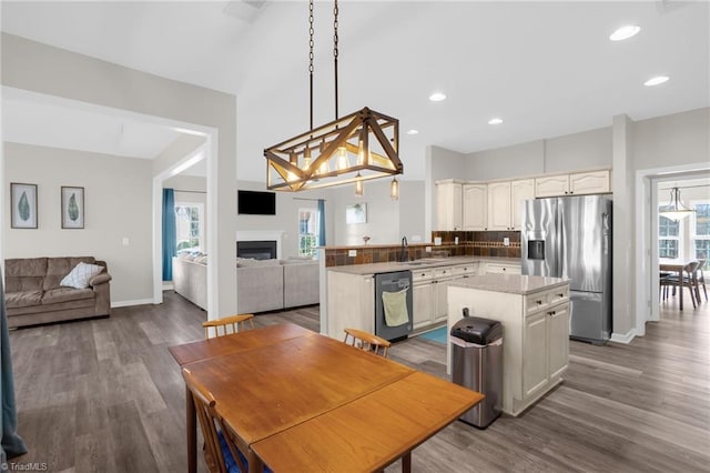 kitchen featuring a kitchen island, open floor plan, a fireplace, wood finished floors, and stainless steel appliances