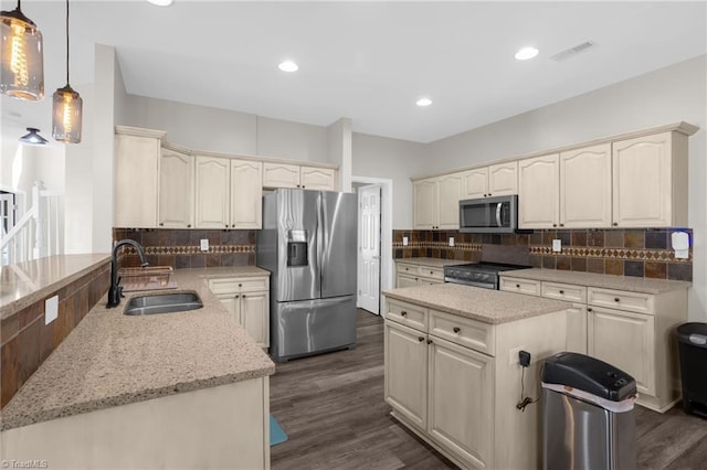 kitchen featuring dark wood finished floors, light stone countertops, stainless steel appliances, and a sink