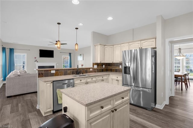 kitchen featuring a sink, open floor plan, a peninsula, appliances with stainless steel finishes, and decorative backsplash