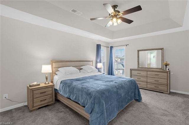 bedroom featuring visible vents, light colored carpet, a raised ceiling, and baseboards