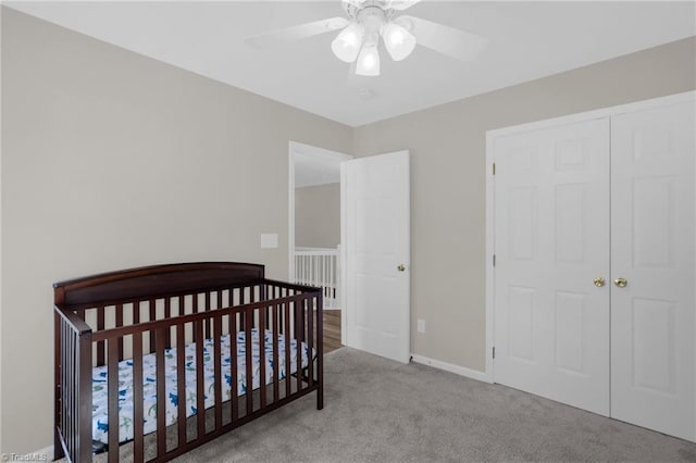 bedroom with a crib, carpet, baseboards, and ceiling fan