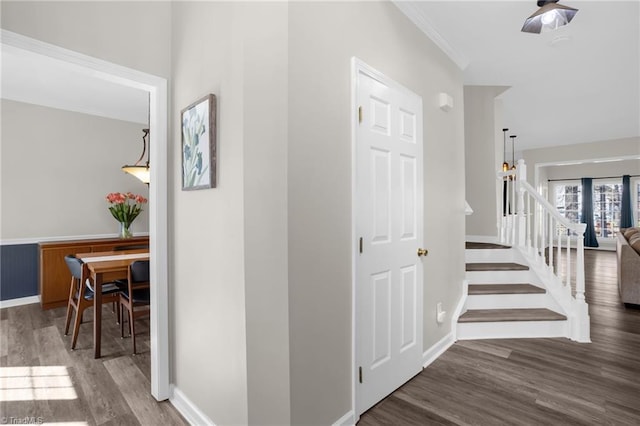 hallway with ornamental molding, stairs, baseboards, and wood finished floors