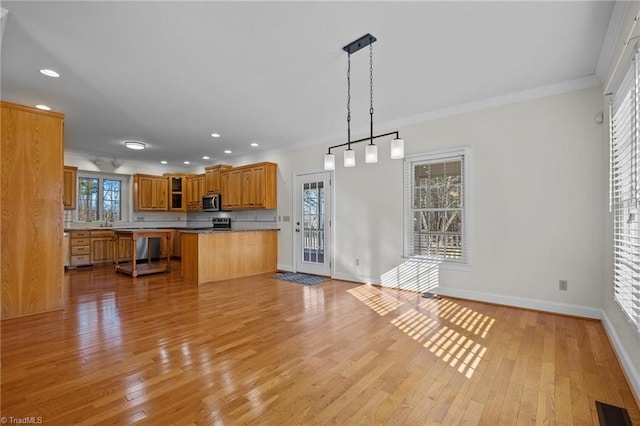 kitchen featuring pendant lighting, sink, crown molding, light hardwood / wood-style flooring, and kitchen peninsula