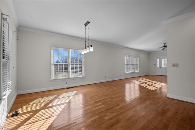 unfurnished dining area with ornamental molding, ceiling fan with notable chandelier, and light hardwood / wood-style flooring