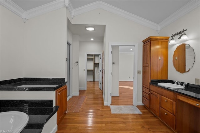 bathroom with ornamental molding, hardwood / wood-style floors, a washtub, and vanity