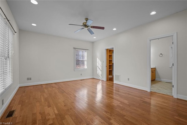 unfurnished bedroom with a spacious closet, connected bathroom, ceiling fan, and light hardwood / wood-style flooring