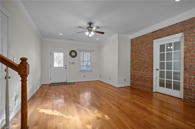 foyer with ceiling fan, ornamental molding, brick wall, and light wood-type flooring